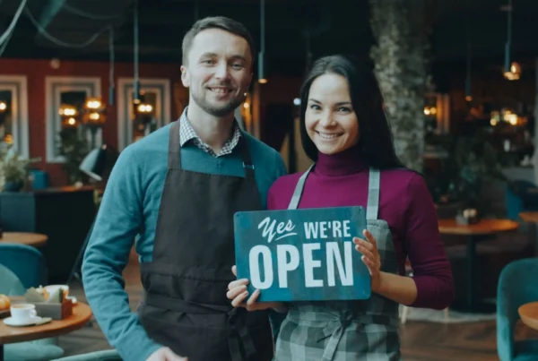 Pemilik restoran memegang papan open saat grand opening restoran baru